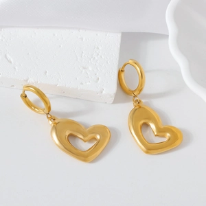 Boucles d'oreilles cœur évidé dorées minimalistes présentées sur socle de pierre