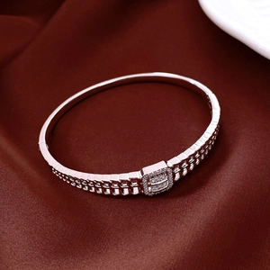 Vue macro d'un bracelet ouvert argenté avec zircon cubique rectangulaire sur satin
