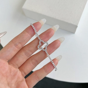 Detail shot of a silver tennis bracelet with a micro-pave clover charm and zircon stones