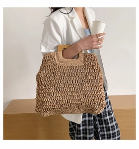 Macro detail of the woven straw texture and square wooden handle of the large tote bag