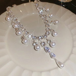Macro shot of a silver water drop zircon and pearl necklace on a ceramic plate