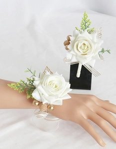 Detail of white satin wedding boutonniere and wrist corsage with green leaves and gold berries
