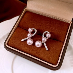 Detail view of wavy silver earrings with sparkling zircons and three pink pearls