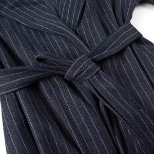 Dettaglio del nodo in vita su un cappotto lungo in lana blu navy a righe sottili