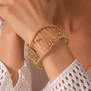 Gros plan d'un bracelet doré multi-rangs avec perles facettées porté par un mannequin