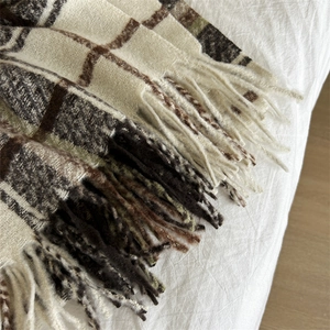 Detailed close-up of soft plaid scarf texture with elegant fringes and woven pattern