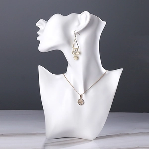 Resin bust jewelry holder with golden tassel earrings and rhinestone crown necklace
