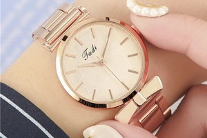 Close-up of rose gold watch featuring a minimalist leaf textured dial and metal strap
