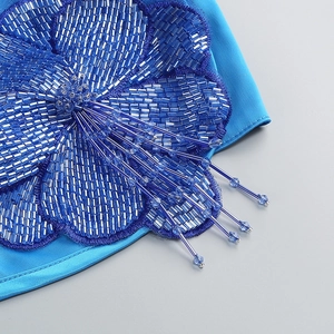 Vue macro détaillée de fleur en perles bleues artisanales sur tissu satiné de robe