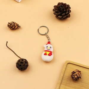 Cartoon snowman PVC keychain with red hat and scarf on warm orange background