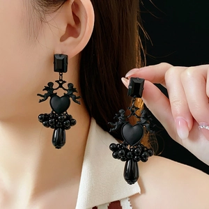 Close-up of black vintage heart earrings with angel charms and beaded tassels on a model