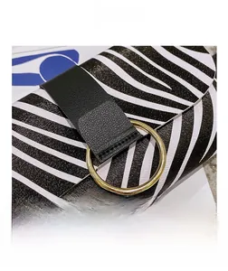Detail shot of animal print handbag with black leather strap and gold circular metal buckle