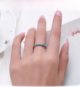 Close-up of a silver band ring with alternating turquoise stones worn on a hand