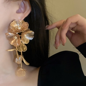Close-up of golden multi-layered flower earrings with long fringe on a female model