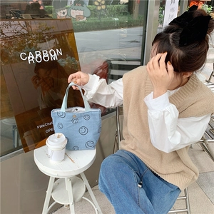 Close-up of light blue corduroy tote bag with black smiley faces and metal snap button