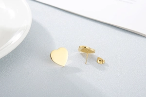 Macro shot of gold stainless steel heart stud earrings with polished finish and backings