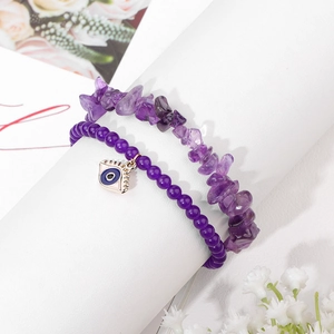 Detail of purple amethyst gravel bracelet and evil eye pendant on white prop