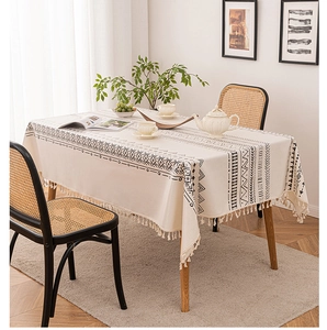 Close-up of bohemian beige tablecloth featuring black geometric patterns and tassel edges