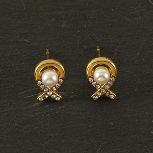 Macro detail of gold 18K stainless steel pearl earrings with crisscross crystal accents