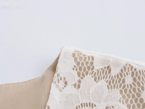 Detail shot of elegant white lace embroidery on beige plain fabric with refined stitching