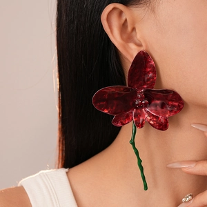 Macro detail of vintage red floral earring with crystal center and green wavy stem