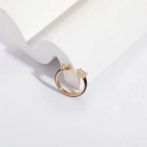 Golden teardrop zircon ring with black enamel finish on a minimalist white stand