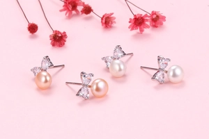 Detailed view of bow stud earrings with heart zircons and natural freshwater pearls