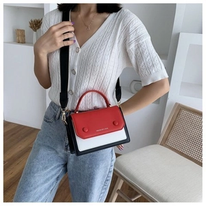 Detail of red, white and black contrast color bag with a wide strap and round buckle