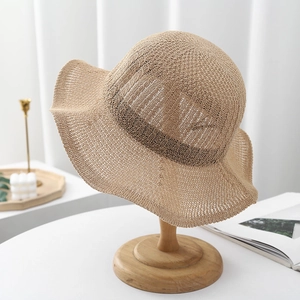 Detail view of khaki knit sun hat with hollow texture on a modern minimalist display stand