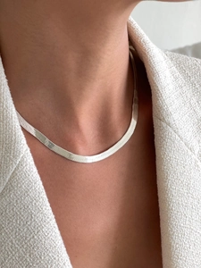 Detailed close-up of 4mm silver snake bone chain necklace worn on neck with white tweed jacket