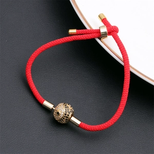 Macro detail of red woven rope bracelet with gold-plated yin yang cubic zirconia charm
