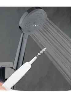Detail of a white small crevice brush cleaning shower head nozzles on a gray tile background