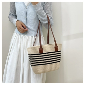 Grande borsa tote intrecciata a righe nere e manici in pelle indossata con outfit estivo
