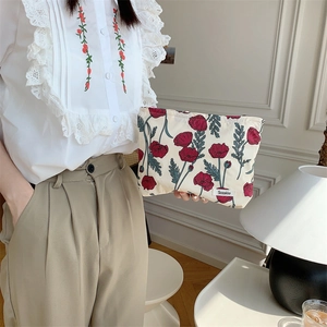 Close-up of a floral cotton makeup bag held by a model in a vintage interior setting