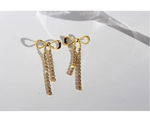 Close-up of golden bow earrings with sparkling rhinestone tassels in Rococo style
