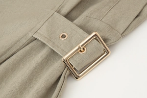 Detailed macro view of the waist belt with gold rectangular buckle on linen dress