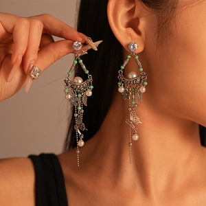 Vintage silver tassel earrings with pearls, leaf charms and butterfly details worn by model