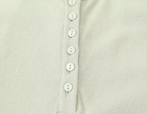 Detailed macro view of sage green ribbed cotton top with single-breasted buttons
