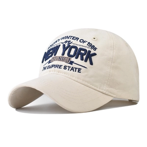 Detailed close-up of blue New York embroidery on a vintage cream washed cotton baseball cap