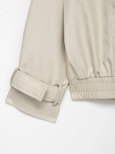 Close-up of cuff straps and elastic drawstring hem on a beige short waterproof windbreaker