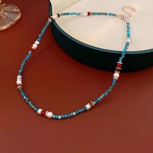 Detail of multi-color beaded pearl necklace on a green jewelry box lid with extension chain