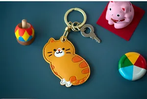Détail d'un porte-clés chat en cuir orange avec anneau métallique doré et fermoir à ressort