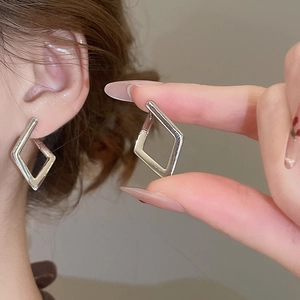 Macro detail of geometric silver rhombus hoop earrings with a polished mirror finish
