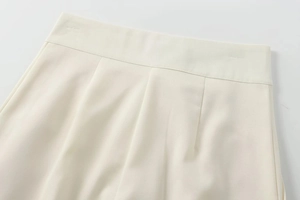Détails rapprochés d'un pantalon blanc taille haute en tissu sergé avec plis élégants