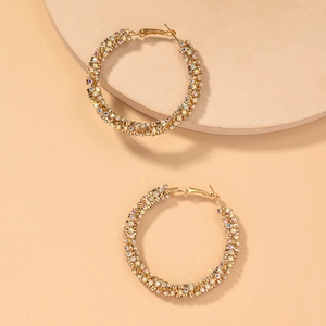 Detailed macro view of large gold hoop earrings encrusted with colorful pavé rhinestones