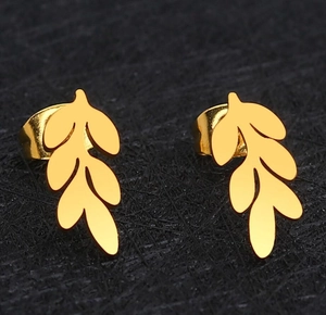 Macro shot of gold leaf-shaped stud earrings with metallic luster on black fabric