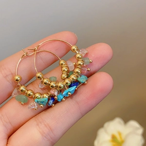 Detail of gold hoop earrings with colorful natural stone beads and metal accents