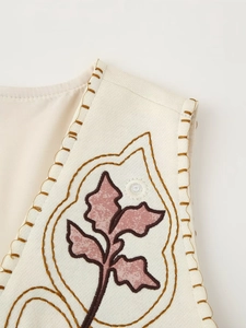 Detail of floral embroidery on a vintage beige mirrored vest with cotton-linen texture