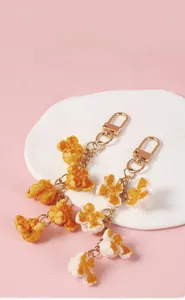 Close-up of realistic PVC popcorn keychains in yellow and red on a ceramic plate