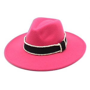 Detail of rose pink wide brim wool fedora hat featuring black ribbon and pearl trim